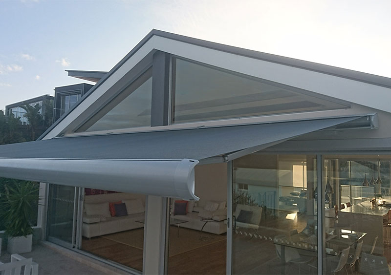 Attached to a glass house is a gray awning.