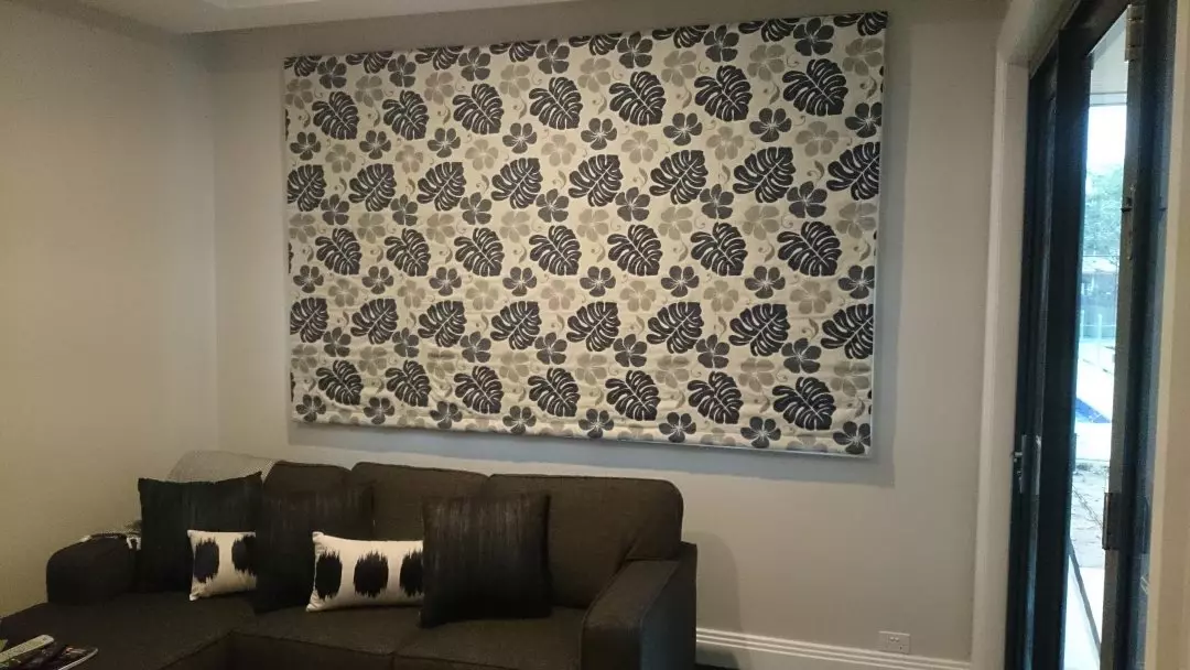 Roman blinds with a leaf pattern and a dark brown couch 